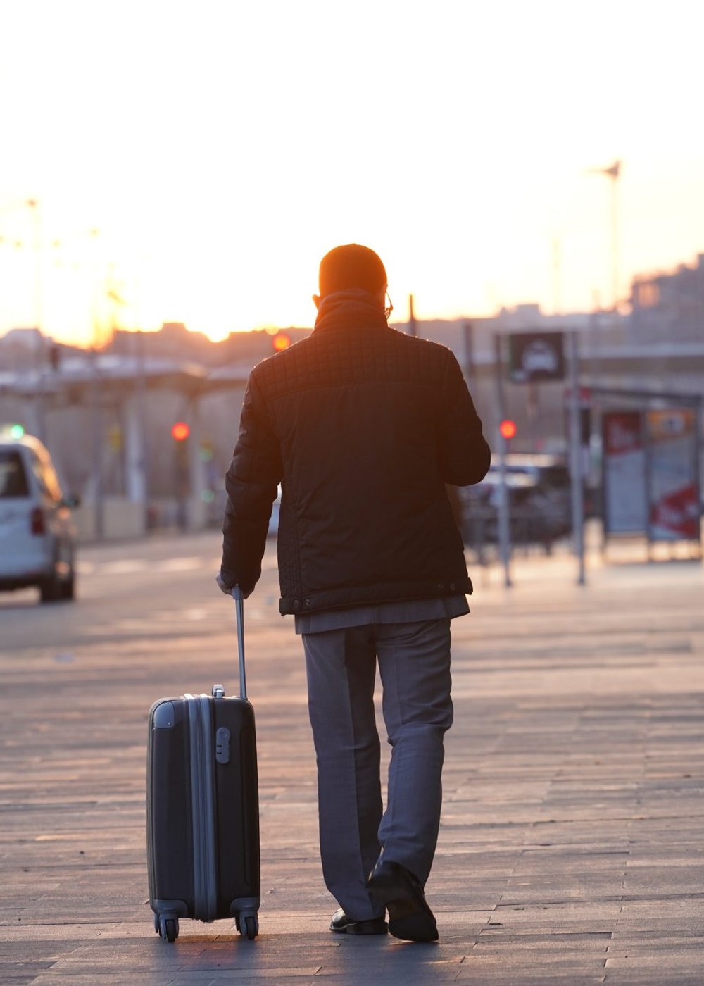 A traveller walking through a European city at golden hour with a wheeled suitcase